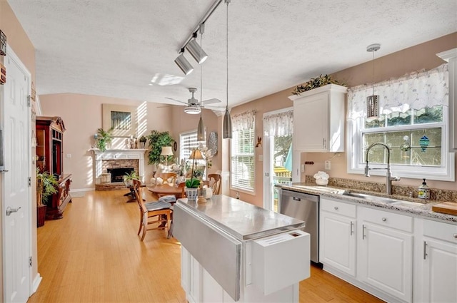 kitchen with white cabinets, hanging light fixtures, a fireplace, a textured ceiling, and light hardwood / wood-style floors