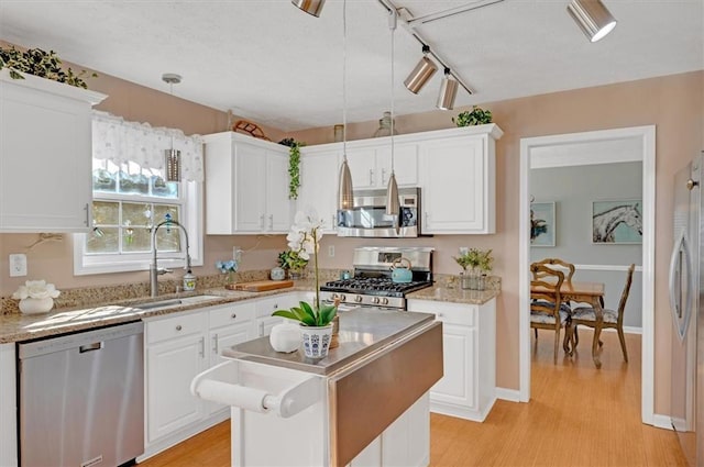 kitchen with sink, white cabinetry, stainless steel appliances, and hanging light fixtures