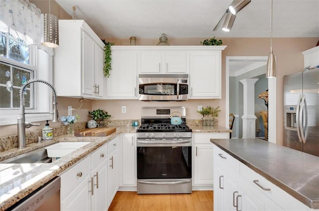 kitchen with white cabinets, sink, light hardwood / wood-style flooring, appliances with stainless steel finishes, and decorative light fixtures