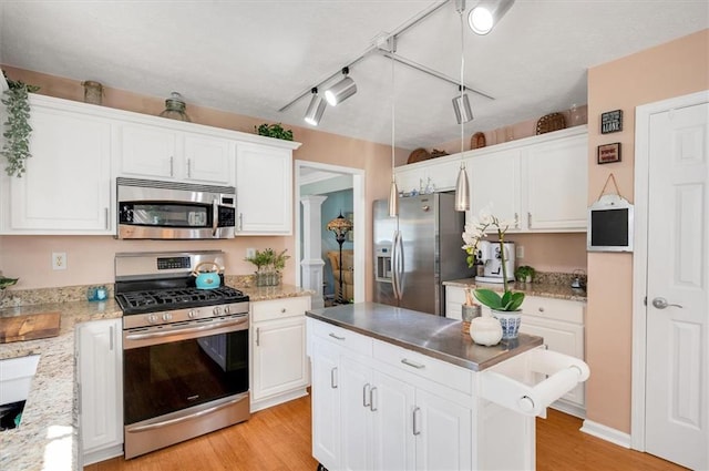 kitchen with a center island, rail lighting, stainless steel appliances, white cabinets, and light wood-type flooring