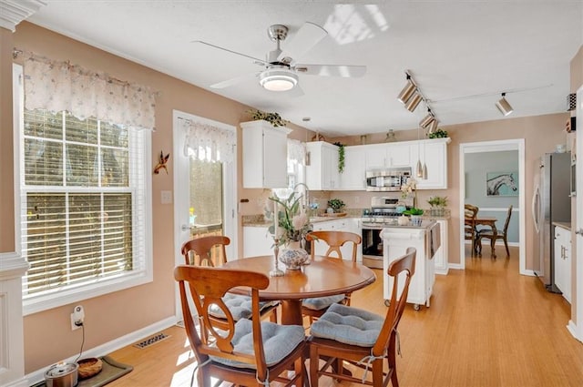 dining area featuring plenty of natural light, rail lighting, and light hardwood / wood-style flooring