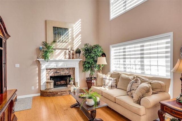 living room featuring a fireplace, a towering ceiling, and hardwood / wood-style flooring