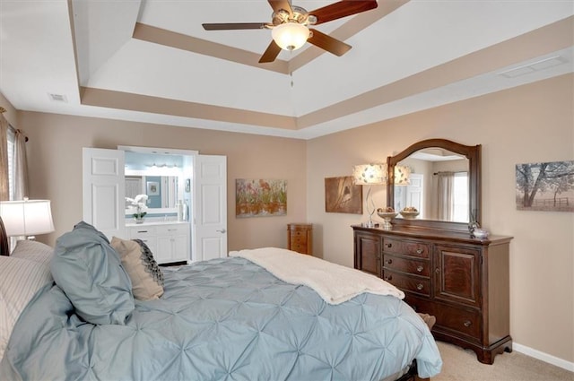 carpeted bedroom featuring ensuite bathroom, ceiling fan, and a tray ceiling