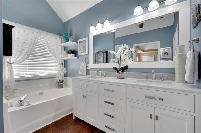 bathroom with a tub, vanity, wood-type flooring, and vaulted ceiling