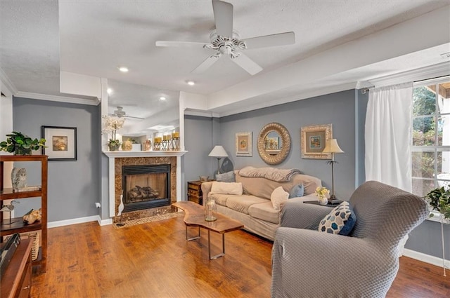 living room featuring hardwood / wood-style floors, ceiling fan, and a fireplace