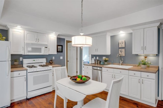 kitchen with sink, dark hardwood / wood-style flooring, pendant lighting, white appliances, and white cabinets