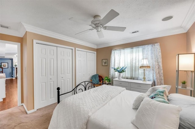 bedroom with a textured ceiling, ceiling fan, light colored carpet, and crown molding