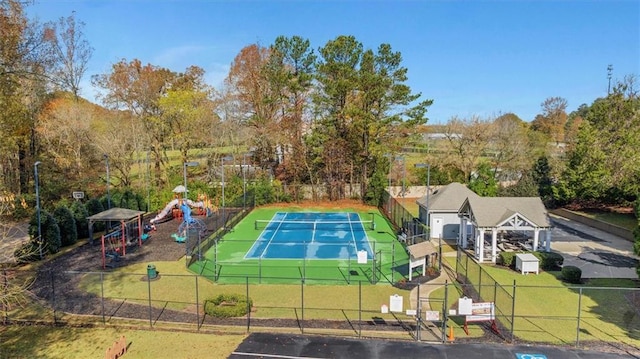 view of tennis court with a playground and a lawn