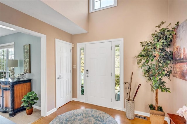 entryway with plenty of natural light, a towering ceiling, and hardwood / wood-style flooring