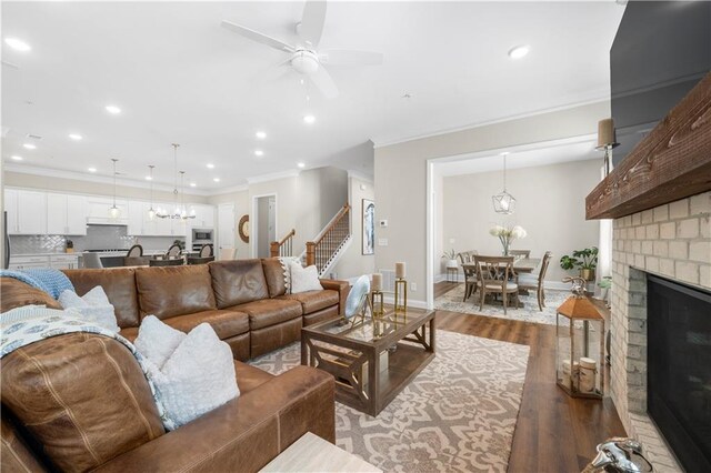 living area with baseboards, wood finished floors, ceiling fan, and ornamental molding