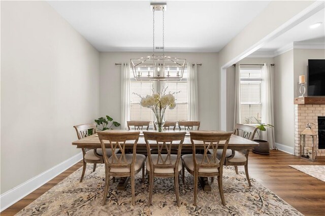 dining area featuring a notable chandelier, baseboards, a fireplace, and wood finished floors
