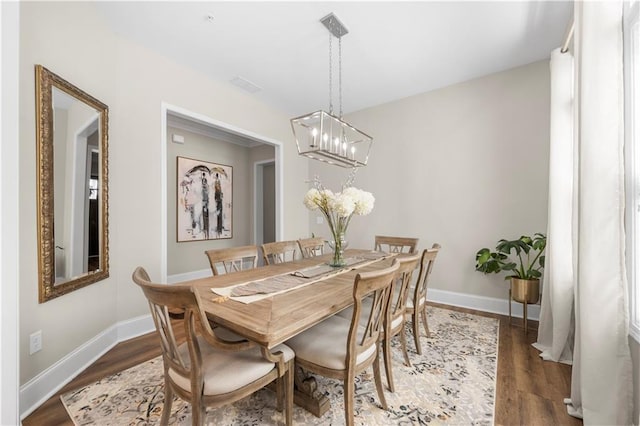 dining room featuring baseboards, wood finished floors, and a chandelier