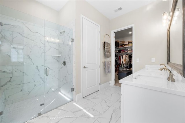 full bath with visible vents, marble finish floor, a marble finish shower, a sink, and a walk in closet