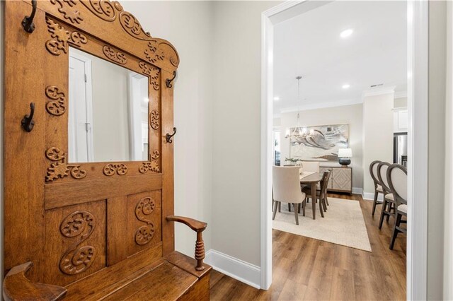 entryway with a chandelier, wood finished floors, baseboards, ornamental molding, and recessed lighting