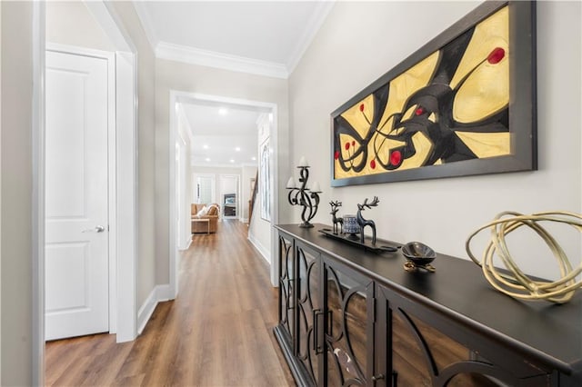 hall featuring baseboards, wood finished floors, and crown molding