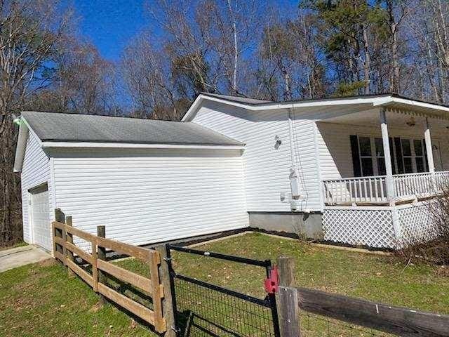 view of home's exterior with driveway, fence, a porch, and a yard