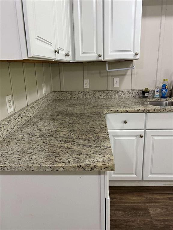 kitchen featuring dark wood-type flooring, light stone counters, sink, and white cabinets