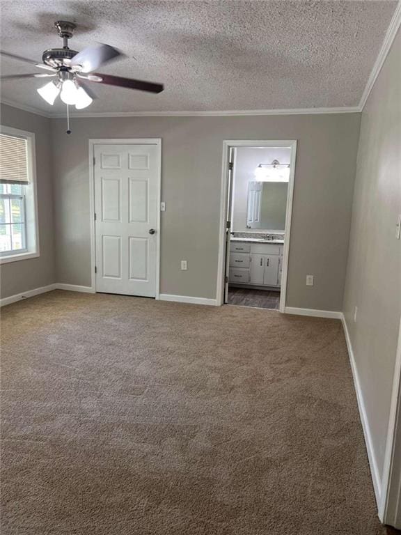 unfurnished bedroom featuring crown molding, dark colored carpet, connected bathroom, a textured ceiling, and baseboards