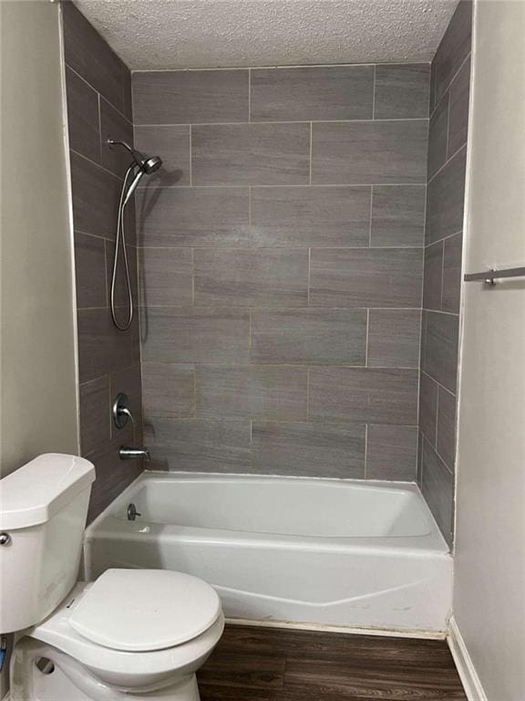 bathroom with toilet, a textured ceiling, wood finished floors, and bathing tub / shower combination