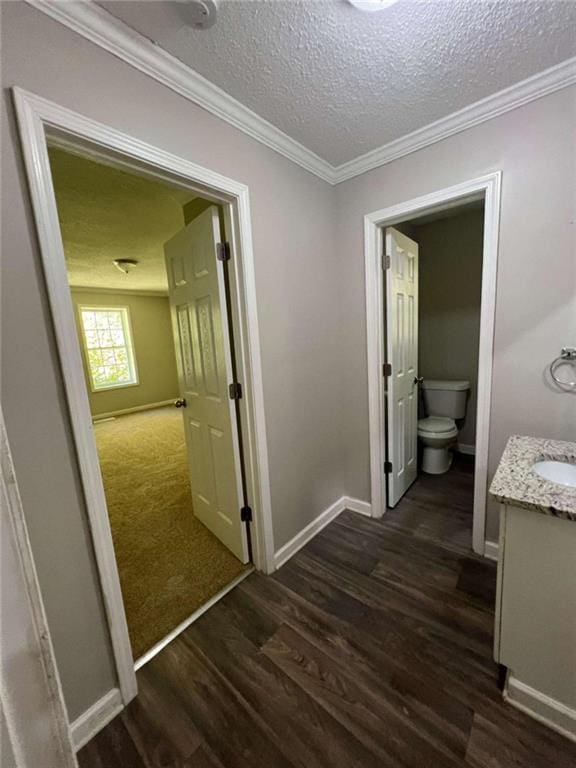 hall featuring ornamental molding, a textured ceiling, sink, and dark wood-type flooring