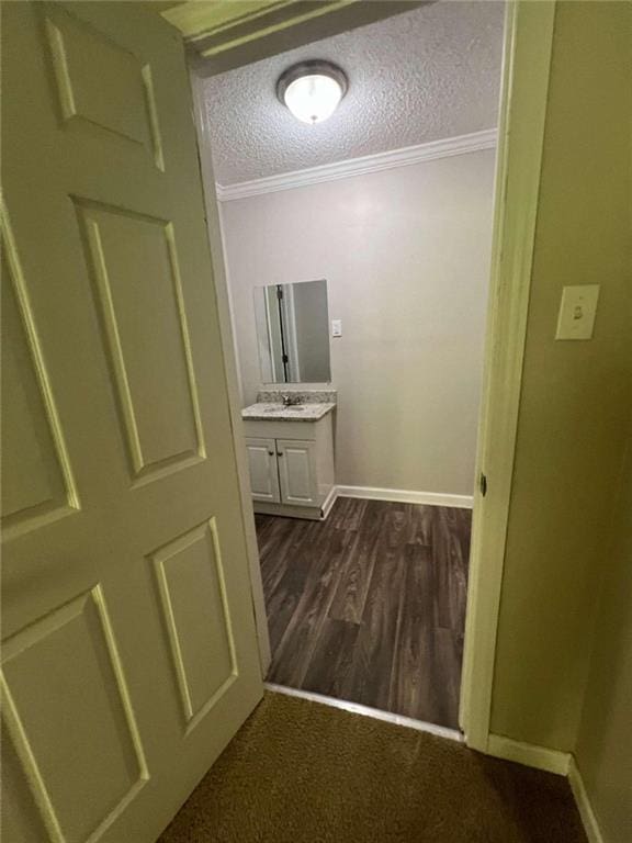 corridor with ornamental molding, dark hardwood / wood-style floors, a textured ceiling, and sink