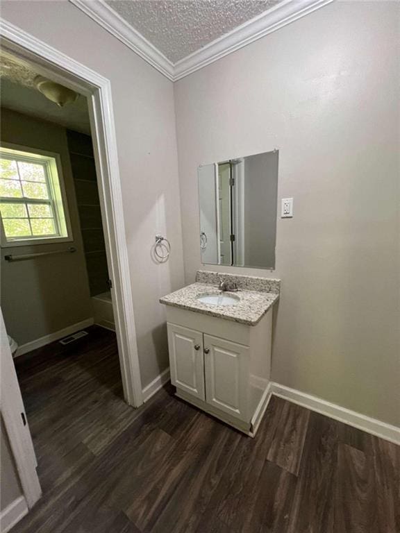 bathroom with a textured ceiling, walk in shower, vanity, crown molding, and hardwood / wood-style flooring