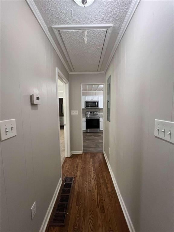 hall featuring ornamental molding, dark wood-type flooring, and a textured ceiling