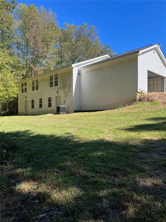 exterior space with a garage, a lawn, and cooling unit