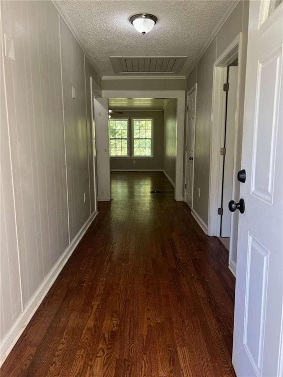 corridor with dark wood-type flooring, visible vents, crown molding, and a textured ceiling