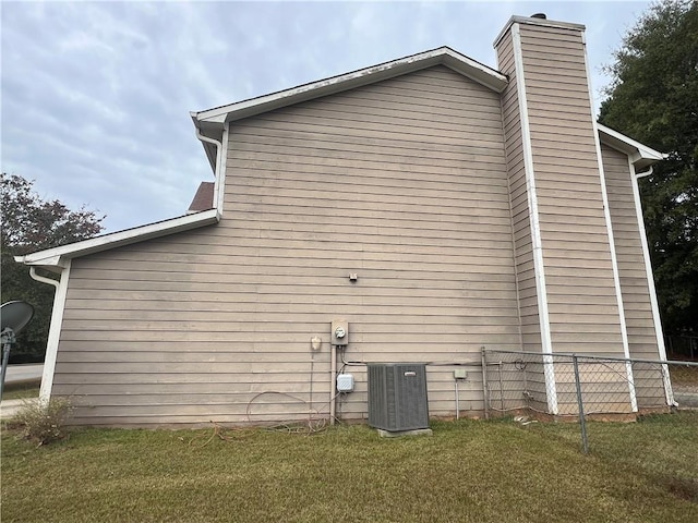 view of side of home featuring central AC and a yard