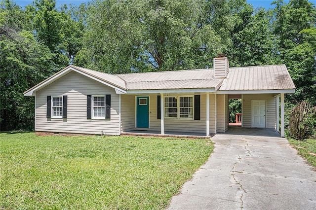 ranch-style home with concrete driveway, an attached carport, a front lawn, and metal roof