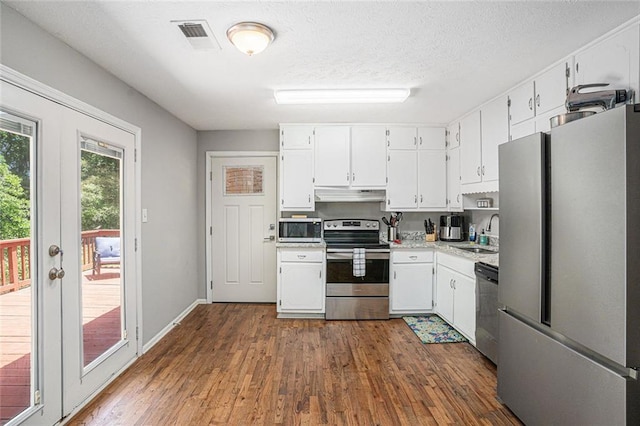 kitchen with stainless steel appliances, under cabinet range hood, a sink, white cabinets, and light countertops
