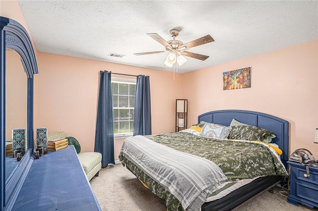 carpeted bedroom with ceiling fan and a textured ceiling