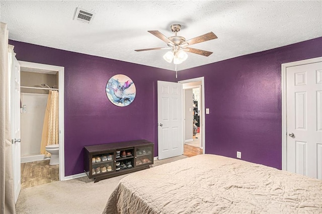 carpeted bedroom with a textured ceiling, baseboards, connected bathroom, and a ceiling fan