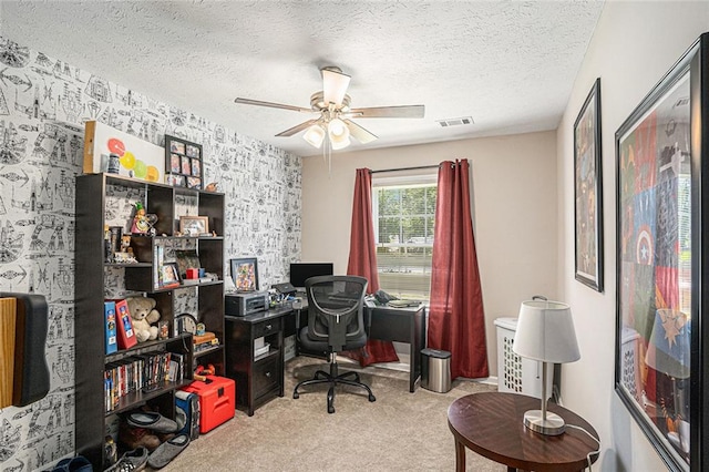 home office with wallpapered walls, an accent wall, carpet, ceiling fan, and a textured ceiling
