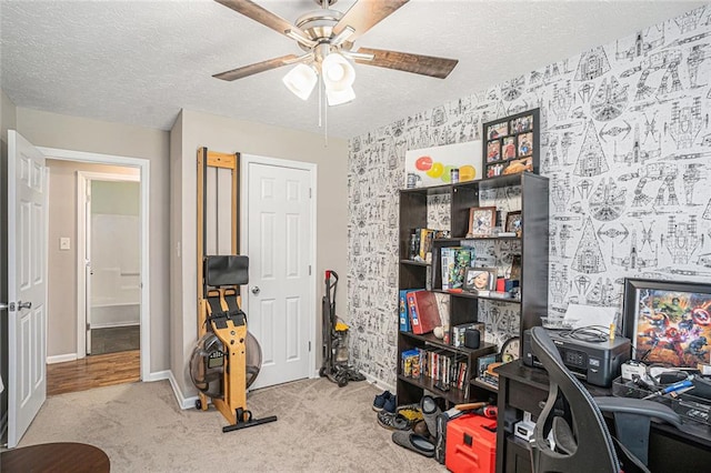 office space featuring a ceiling fan, carpet flooring, baseboards, a textured ceiling, and wallpapered walls