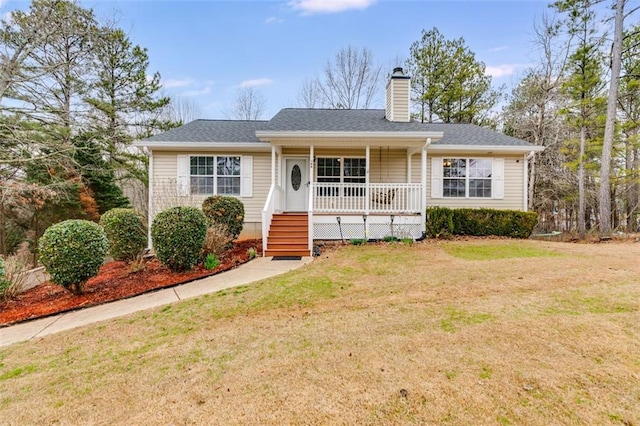 view of front of house with covered porch, roof with shingles, a chimney, and a front yard