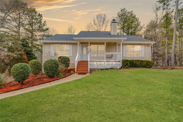 ranch-style house with a porch, roof with shingles, a chimney, and a front lawn