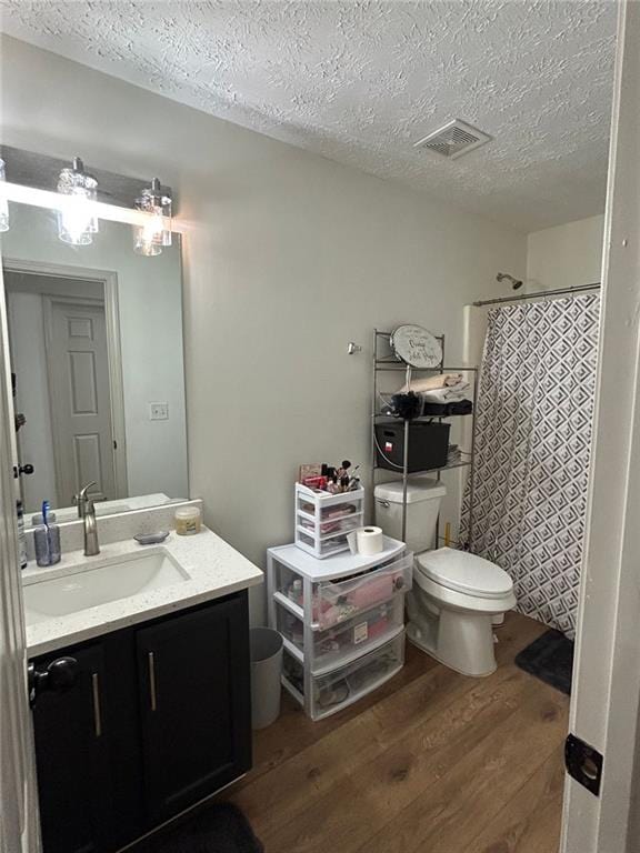 bathroom with toilet, a textured ceiling, vanity, curtained shower, and hardwood / wood-style floors