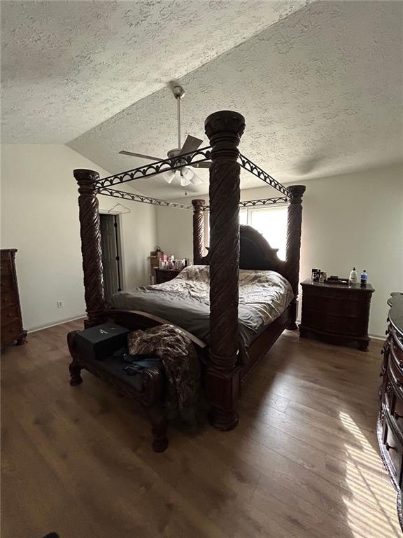 bedroom with lofted ceiling, hardwood / wood-style flooring, and a textured ceiling