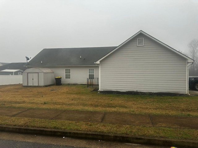 rear view of property featuring a lawn and a storage shed