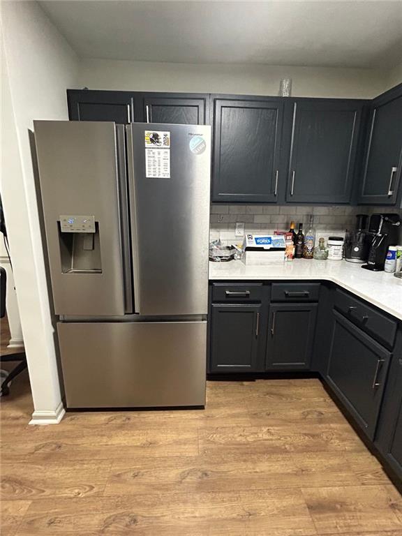 kitchen with tasteful backsplash, stainless steel fridge, and light hardwood / wood-style floors