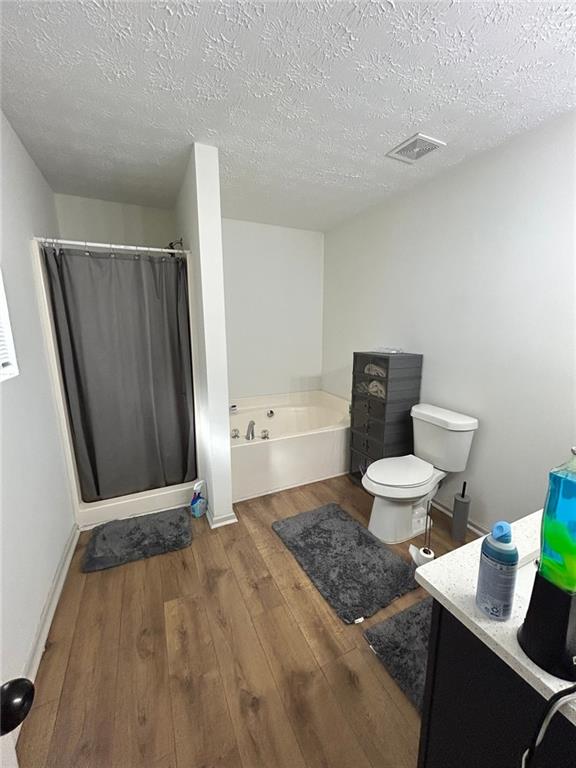 full bathroom featuring hardwood / wood-style flooring, vanity, a textured ceiling, and toilet