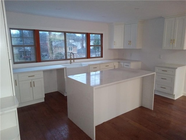 kitchen featuring white cabinets, a kitchen island, dark wood finished floors, and a sink