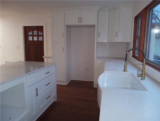 kitchen with light countertops, dark wood-type flooring, a sink, and white cabinetry