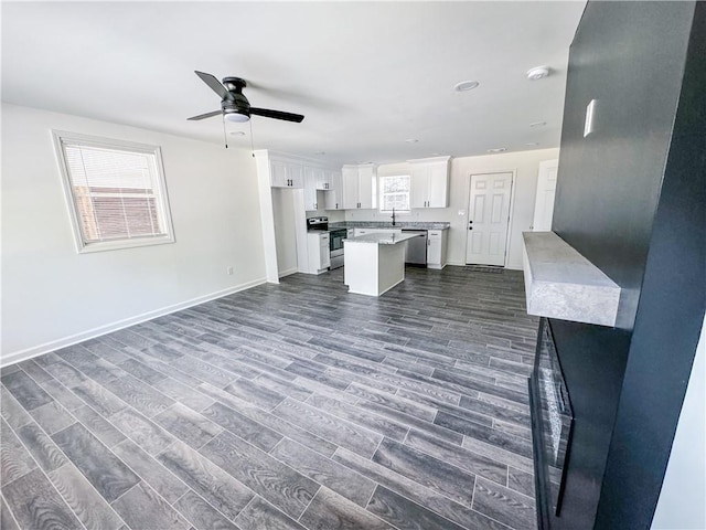 unfurnished living room featuring ceiling fan, dark hardwood / wood-style floors, and sink