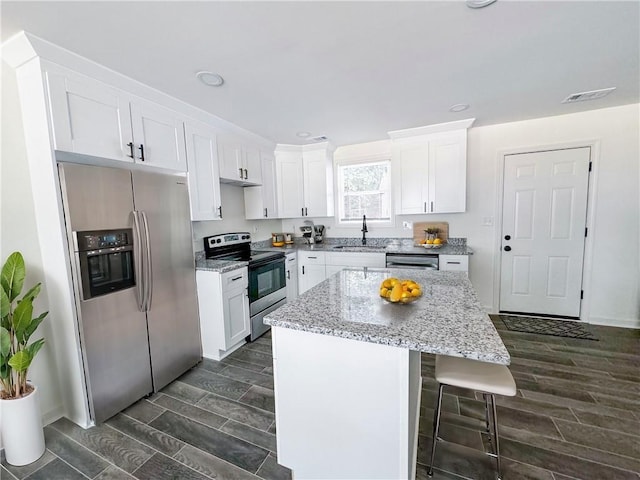 kitchen with white cabinets, sink, a kitchen island, and appliances with stainless steel finishes