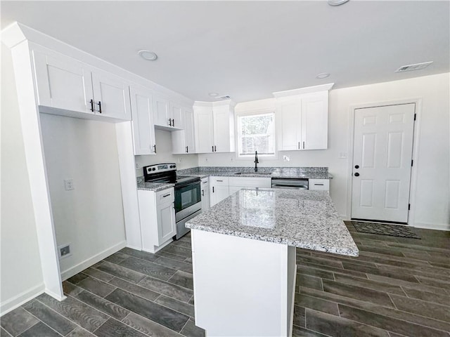 kitchen with light stone countertops, stainless steel appliances, sink, white cabinets, and a center island