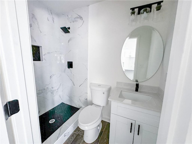 bathroom featuring vanity, toilet, and tiled shower