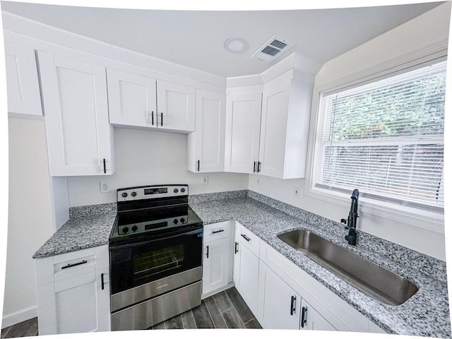 kitchen with white cabinets, stainless steel electric range oven, light stone countertops, and sink